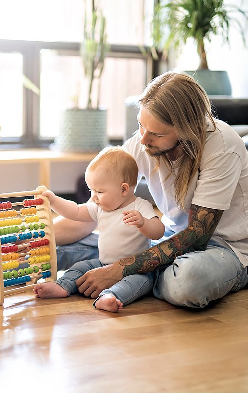 Mann mit Kind spielt auf dem Fußboden