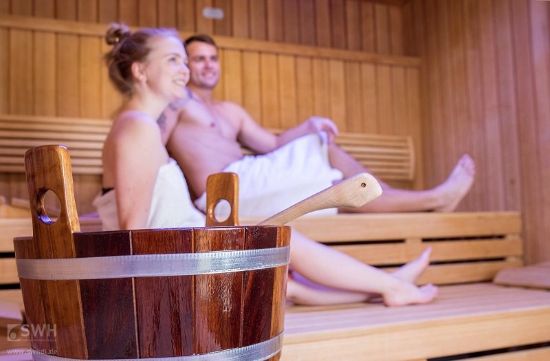 Mann und Frau in der Finnischen Sauna mit einem Aufguss