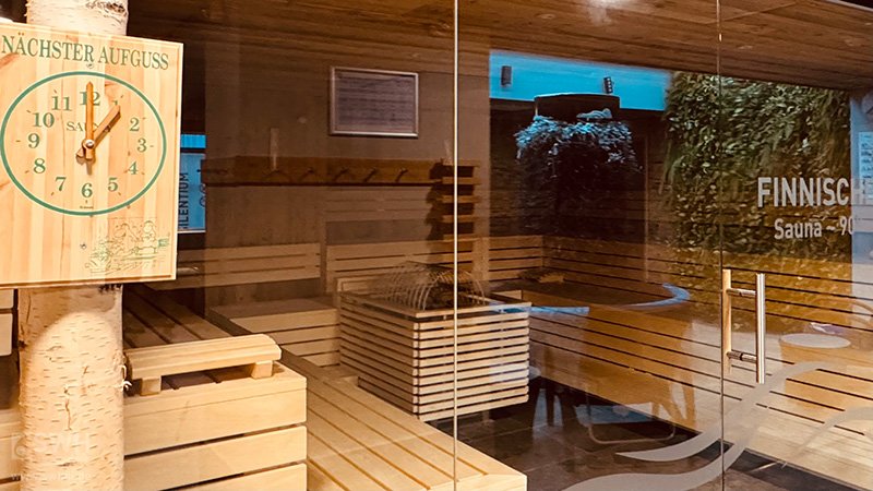 Blick in die finnische Sauna mit der Aufgussuhr am Birkenstamm