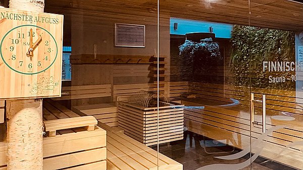 Blick in die finnische Sauna mit der Aufgussuhr am Birkenstamm