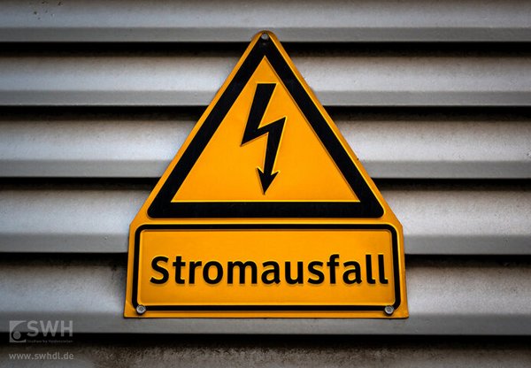 Gelbes Warnschild mit schwarzer Aufschrift Stromausfall und Blitz