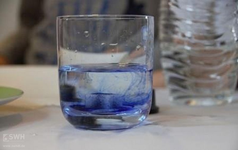 ein blaues Glas mit Wasser steht auf einem Tisch